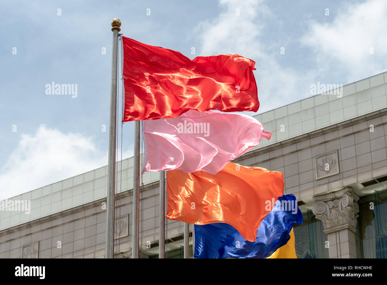 Collezione di bandiere di diversi colori in volo da poli nella facciata di un edificio Foto Stock