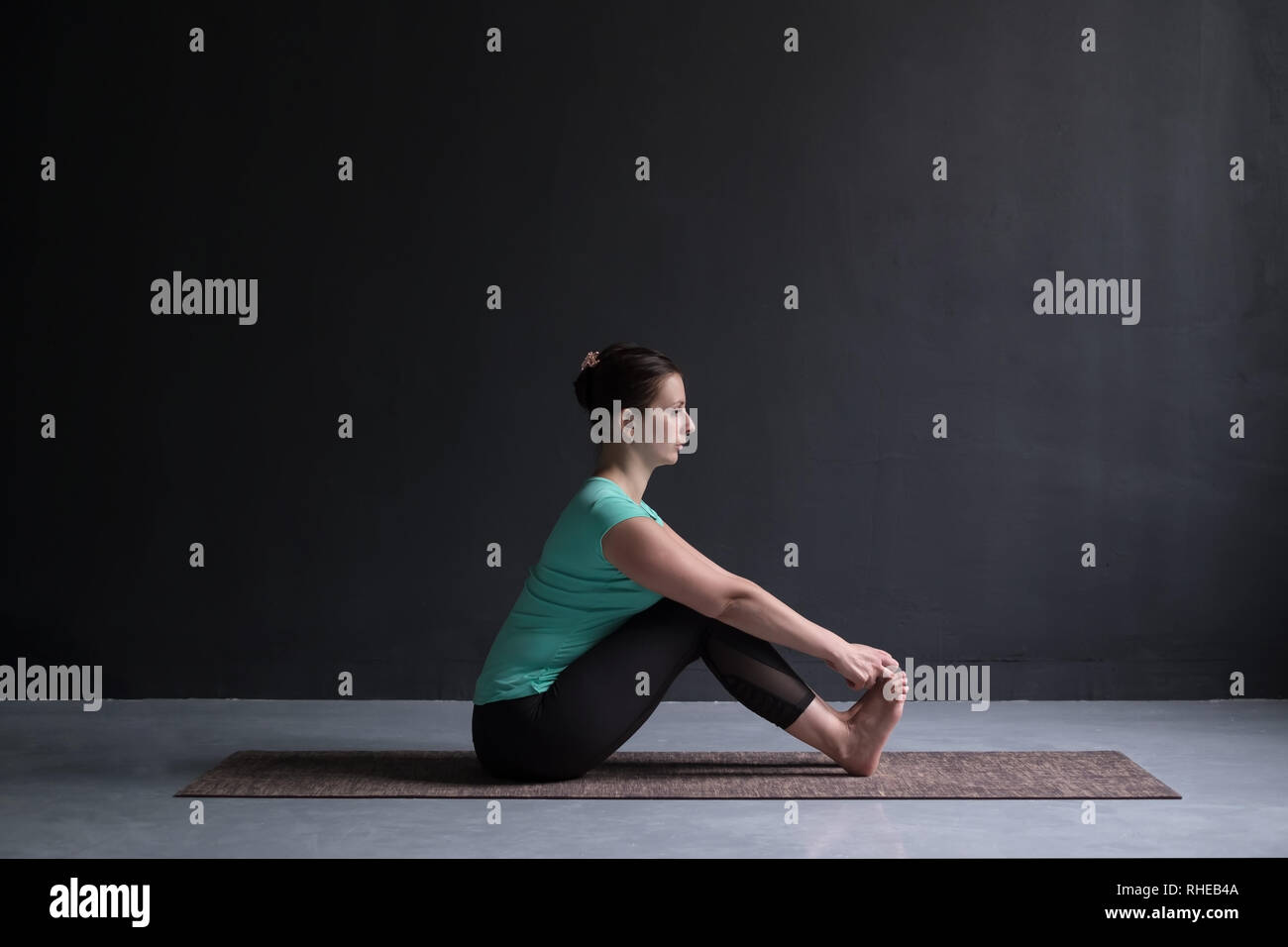 Donna pratica lo yoga, facendo seduti piegare in avanti pone, usando le mani. Foto Stock