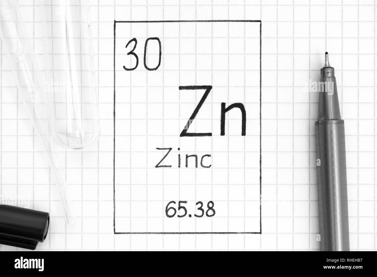 Tavola periodica degli elementi. La grafia elemento chimico zinco Zn con la penna nera, tubo di prova e la pipetta. Close-up. Foto Stock