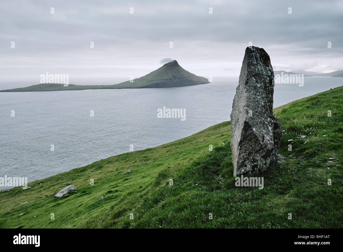 Un solitario pietra permanente su Streymoy affacciato Koltur isola nelle isole Faerøer. Foto Stock