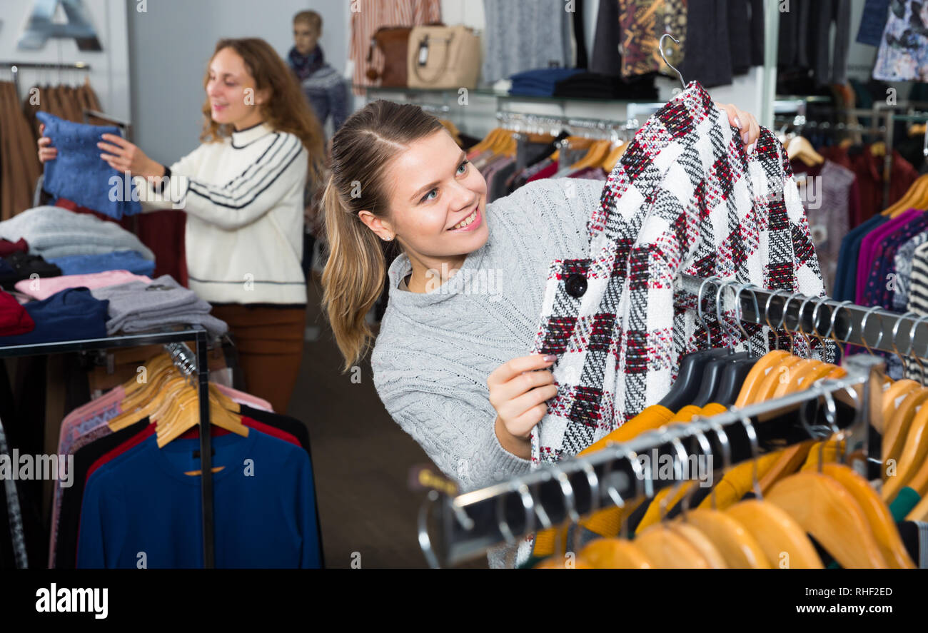 Camera shopping del negozio di abbigliamento con le donne la scelta di cappotti e cardigan Foto Stock