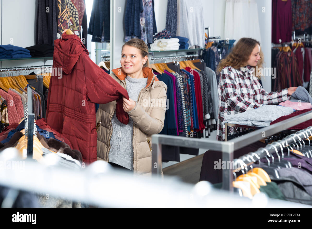 Camera shopping del negozio di abbigliamento con le donne la scelta di cappotti e cardigan Foto Stock