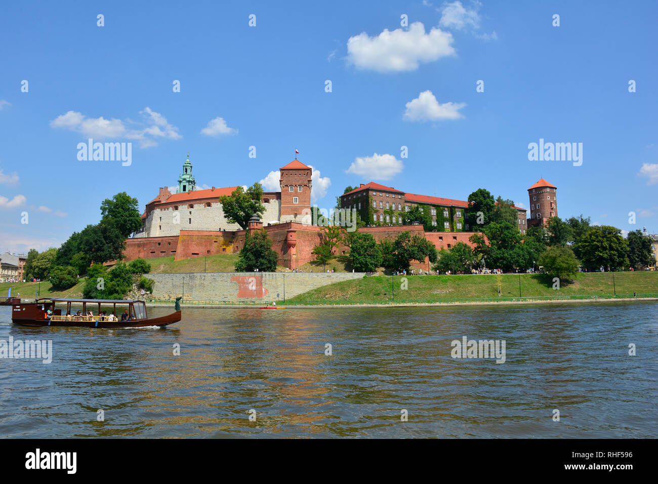 Cracovia in Polonia - 10 luglio 2018. Una barca turistica va passato il Castello di Wawel sul fiume Vistola. Il campanile della cattedrale di Wawel può anche essere visto Foto Stock