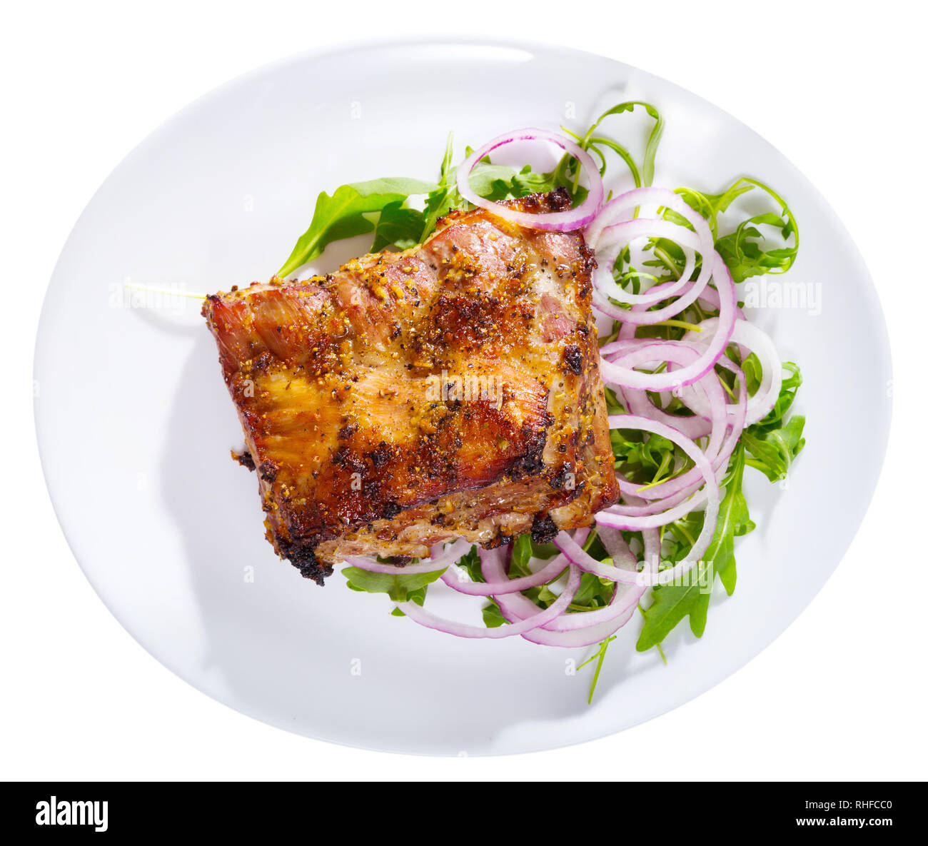 Succosa rack barbecue di carne di maiale servito su foglie di rucola fresca con anelli di cipolla. Isolato su sfondo bianco Foto Stock