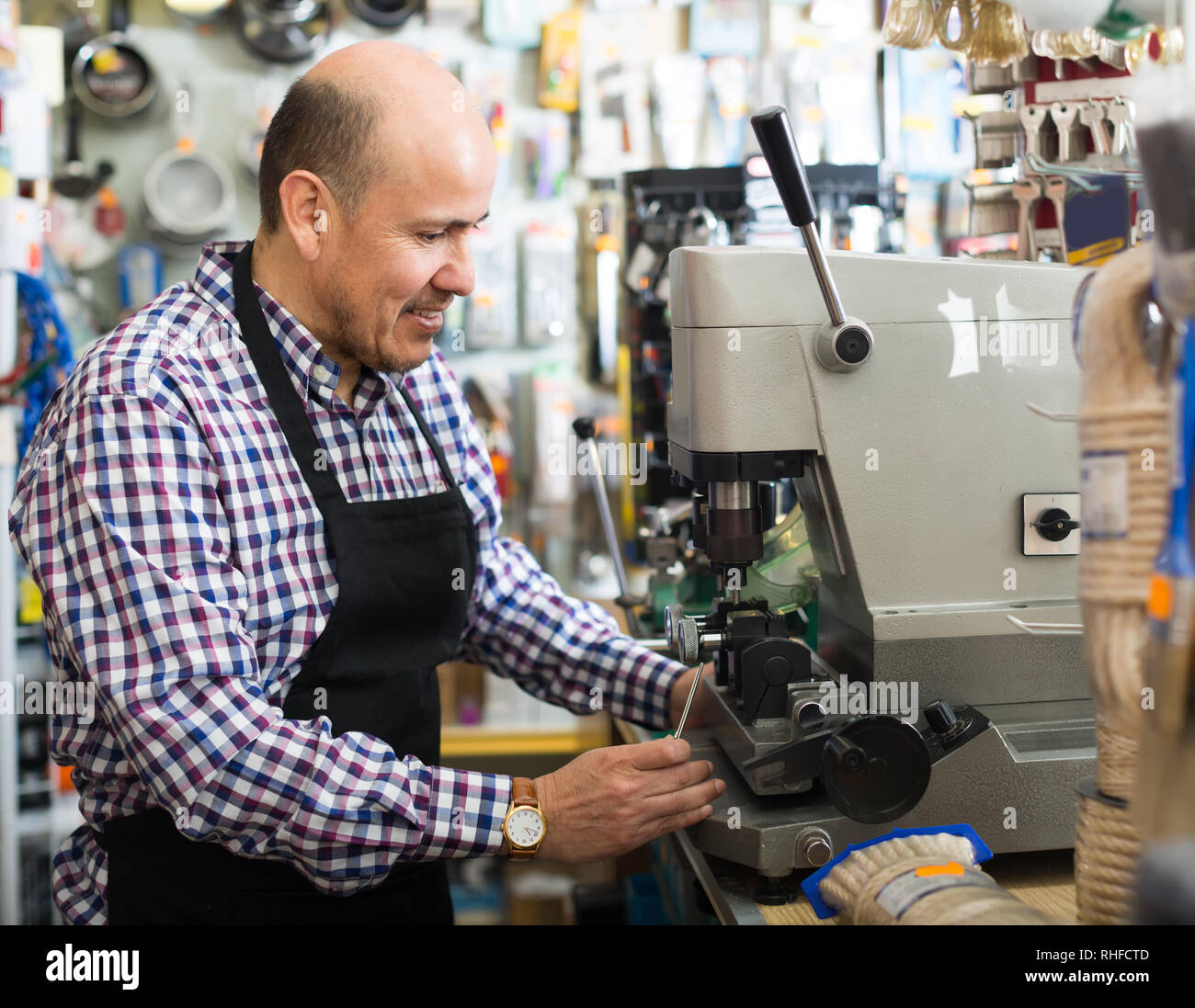 Sorridente uomo maturo nel lavoro di fabbro e rendendo i duplicati di chiavi Foto Stock