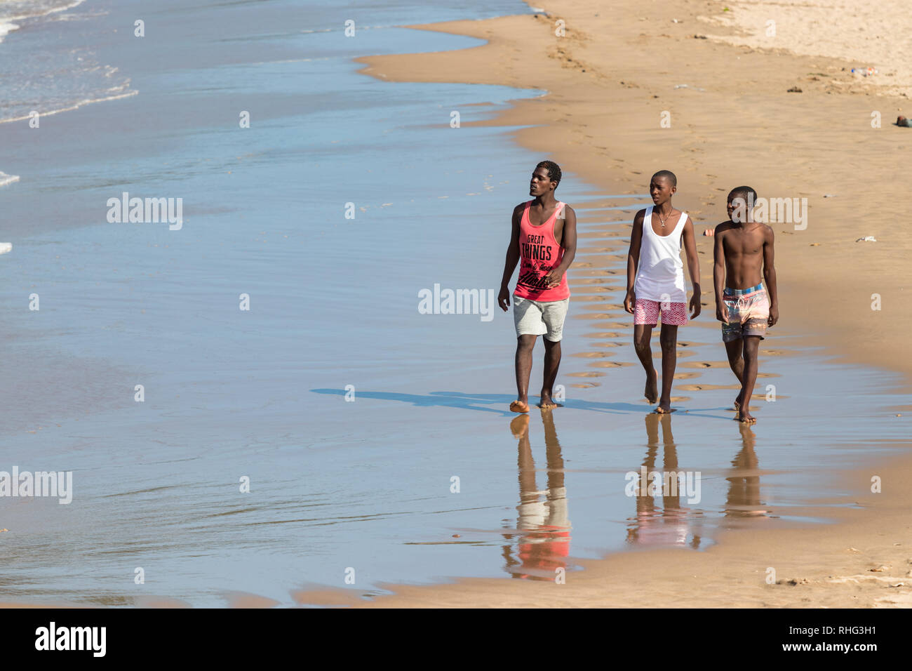 Durban, Sud Africa - Gennaio 7th, 2019: Tre South African uomini neri camminare da solo in spiaggia guardando il mare in una spiaggia a Durban, Sud afri Foto Stock