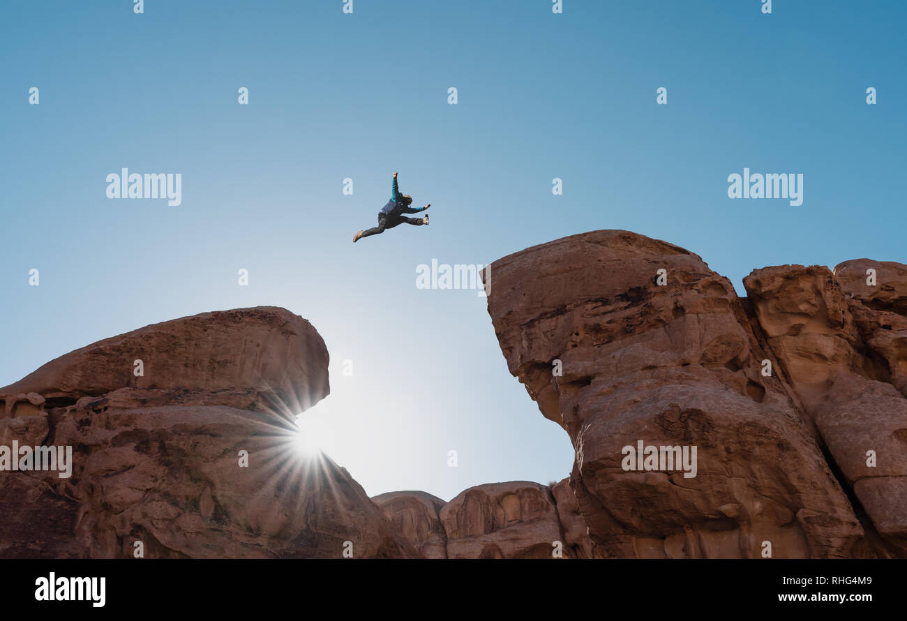 Sfida, rischio e concetto di libertà. La silhouette di un uomo saltando su strapiombo attraversando cliff Foto Stock