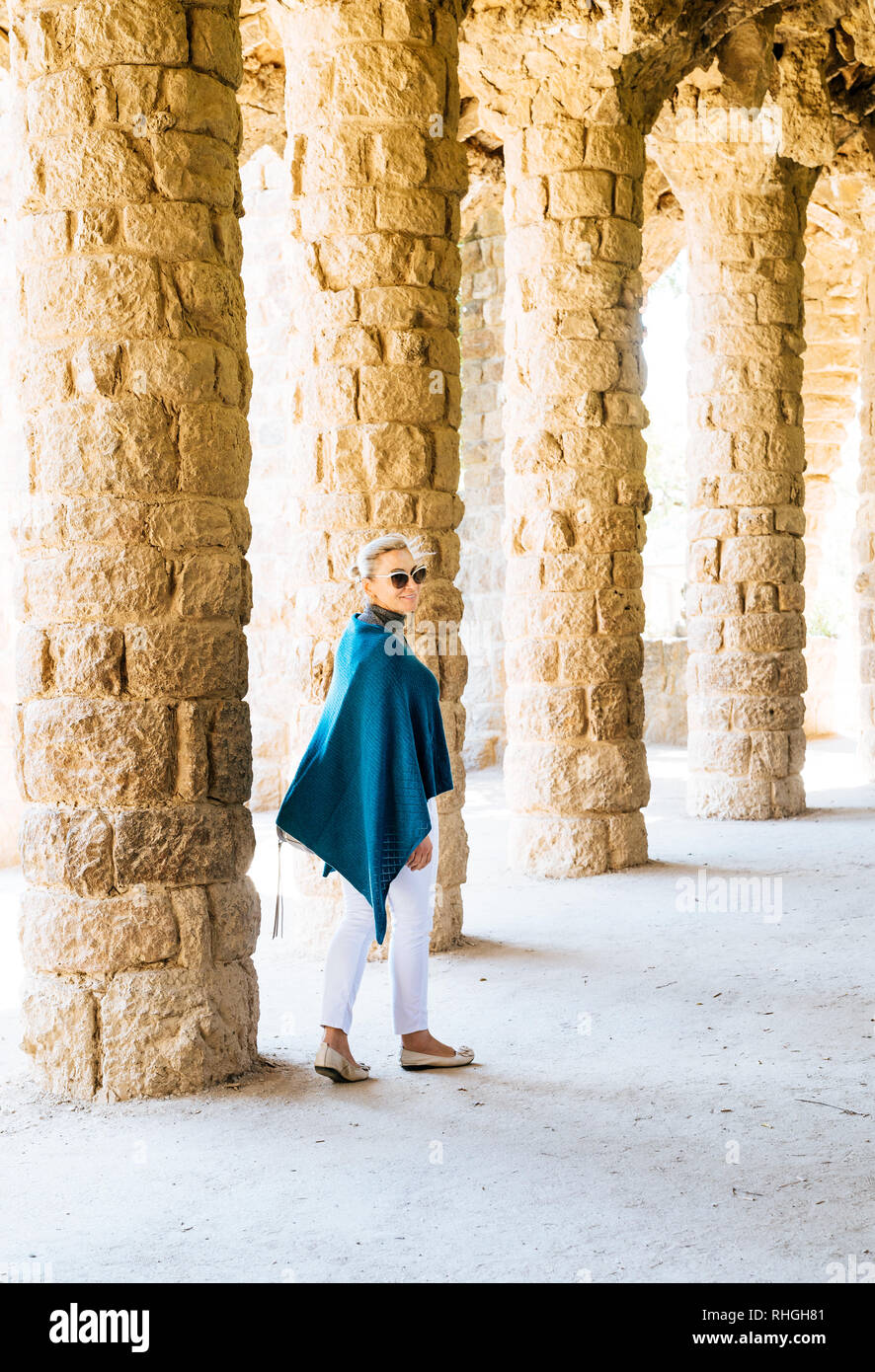 La donna a piedi attraverso un colonnato nel Parco Guell di Barcellona Foto Stock