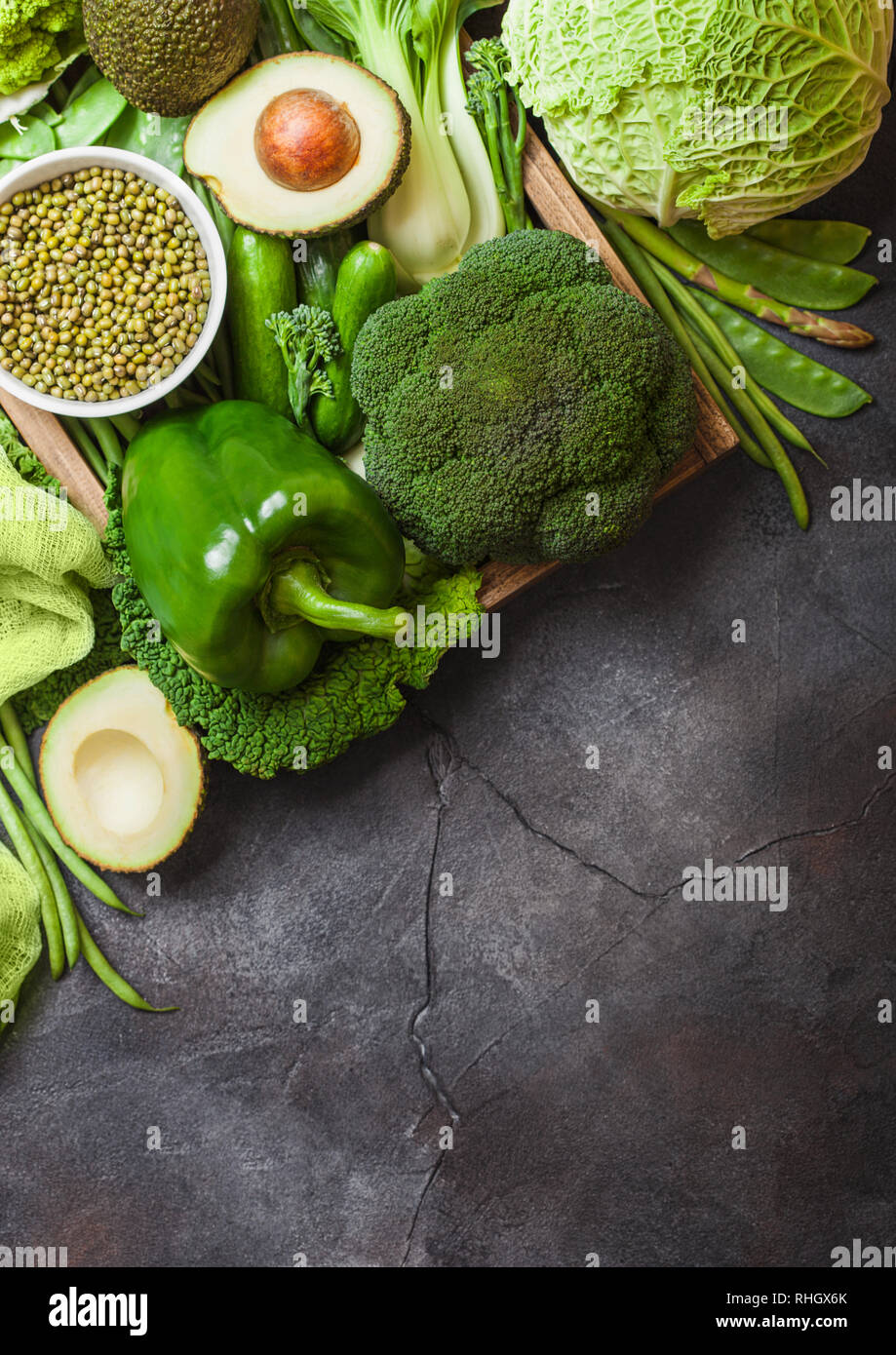 Assortiti nei toni del verde materie verdure organiche su sfondo scuro. Avocado, cavoli broccoli, cavolfiori e cetriolo con fagioli rifilati. Foto Stock