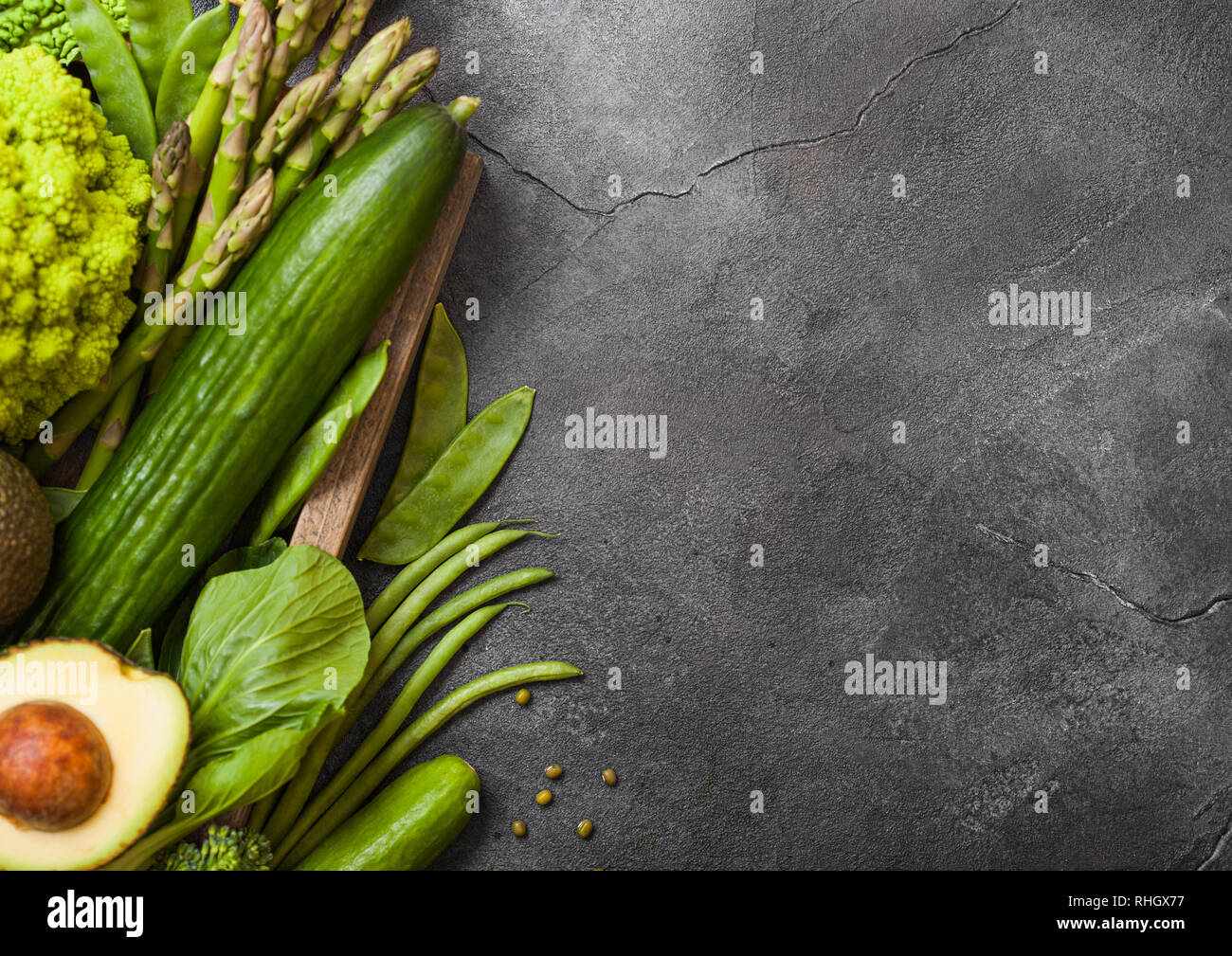 Assortiti nei toni del verde materie verdure organiche su sfondo scuro. Avocado, cavoli broccoli, cavolfiori e cetriolo con fagioli rifilati. Foto Stock