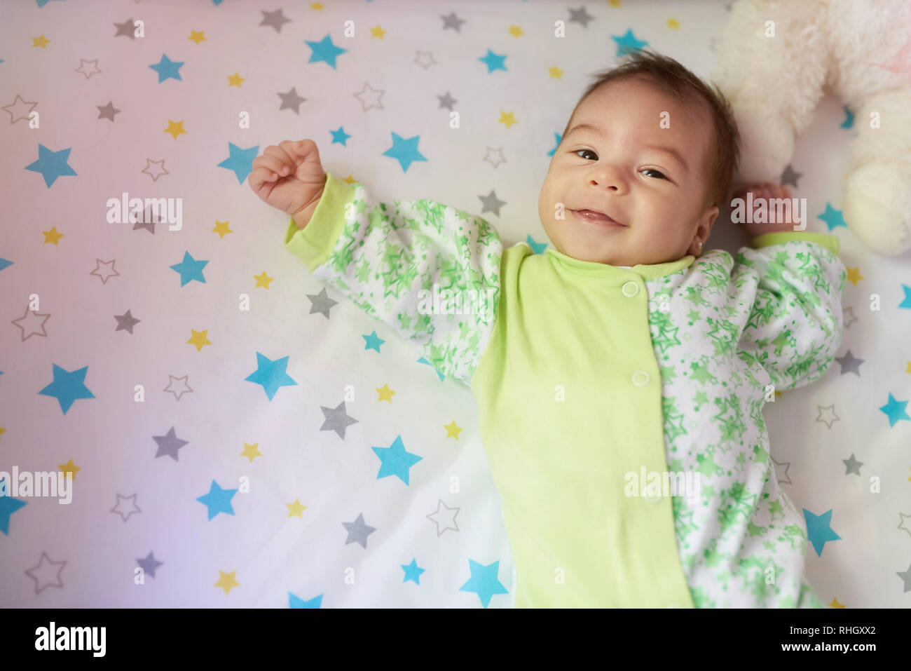 Sorridente bambina posa sul letto sopra vista superiore Foto Stock