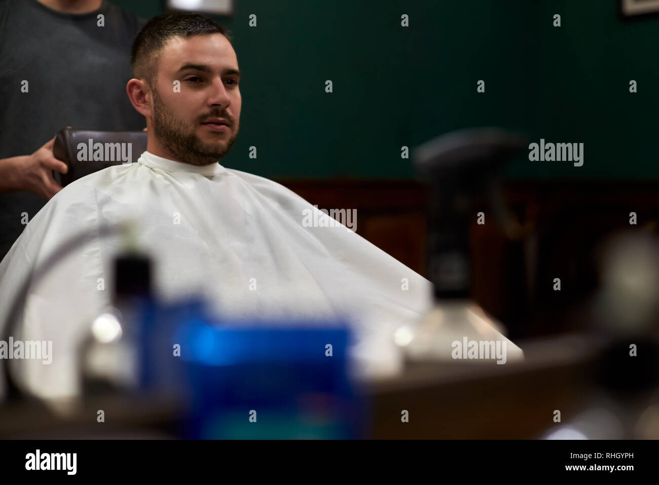 La riflessione di un parrucchiere la mano. Hipster barbuto client riceve i capelli nella parte anteriore dello specchio Foto Stock