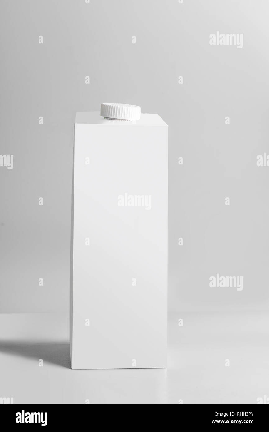 Confezione bianca tetra-pack in piedi su sfondo grigio chiaro, vista frontale. Vuota la casella modello latte o succo di frutta. Branding pacchetto mock-up Foto Stock