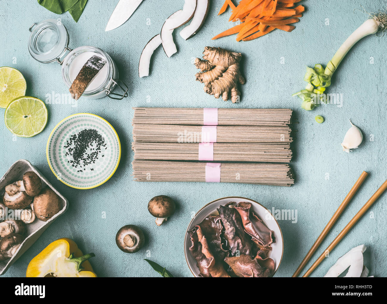 Asian ingredienti alimentari laici piatto sulla luce blu tavolo da cucina background: tagliatelle, verdure, funghi e spezie. Gustosa cucina vegana e mangiare. Mento Foto Stock