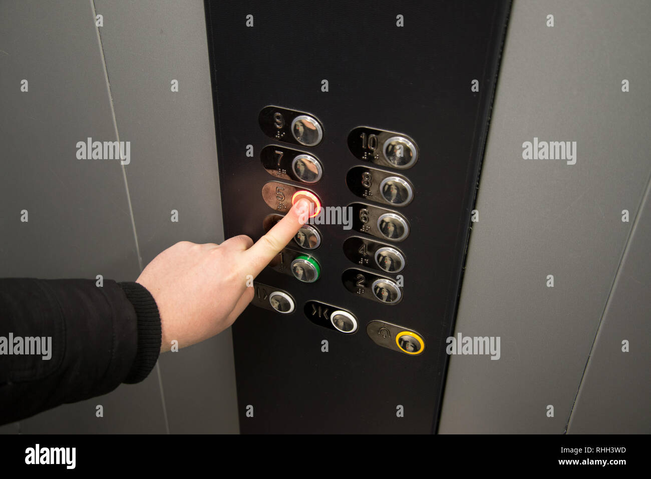 Mano, premendo il pulsante di allarme in ascensore. Foto Stock