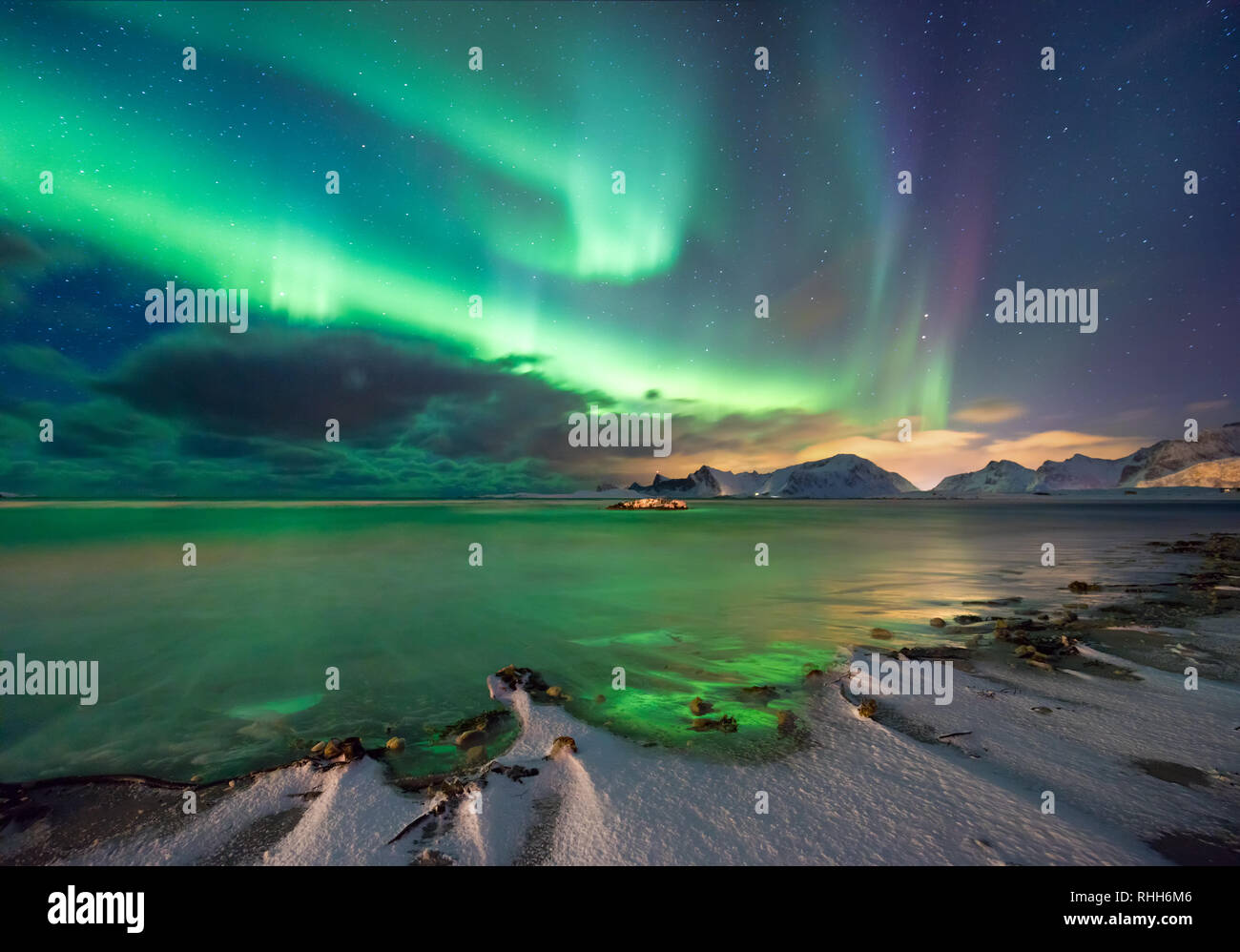 Vera magia di luci del nord - fiordo norvegese con montagne e neve, colore riflessioni sulle onde del mare. Paesaggio invernale, natura settentrionale Foto Stock