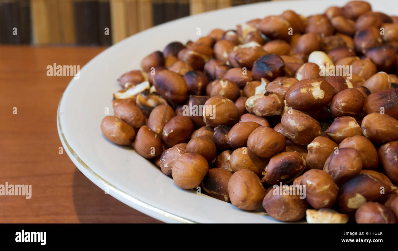 Arachidi tostate Snack nella piastra bianca in sfondi di legno - Тopview ans Closeup Foto Stock