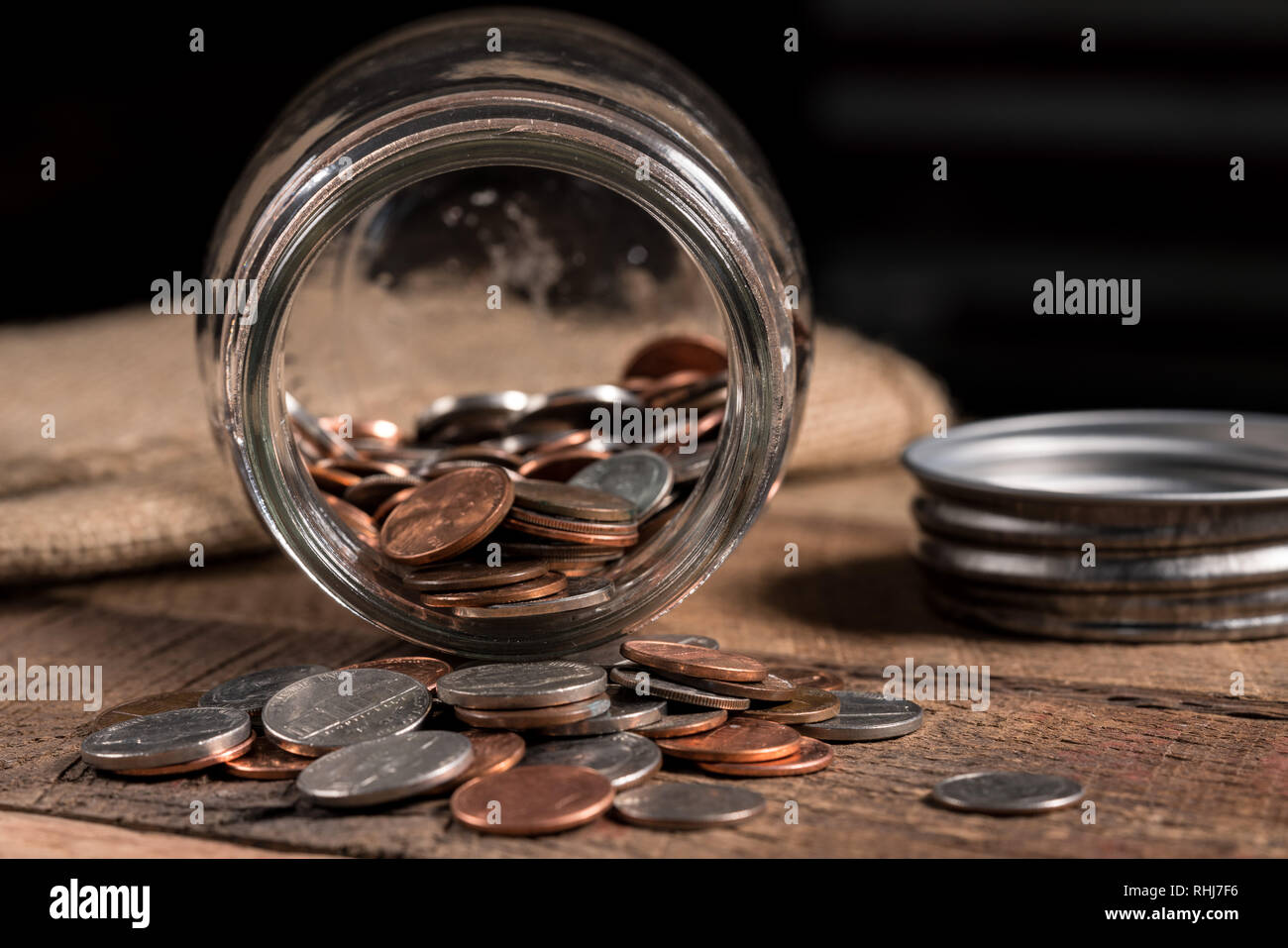 Vetro mason jar con poche monete all'interno per illustrare la povertà Foto Stock