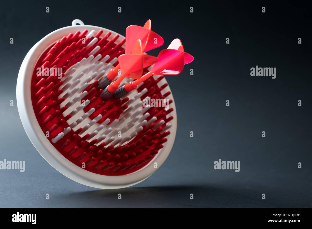 Tre rossi dart frecce di colpire il centro del dartboard per il raggiungimento degli obiettivi concettuali Foto Stock