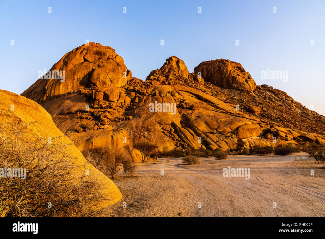 Riserva naturale Spitzkoppe. I pittoreschi archi in pietra dipinta in rosso e arancione. Sole di sera si allunga le ombre tra le rocce roadtrip Foto Stock