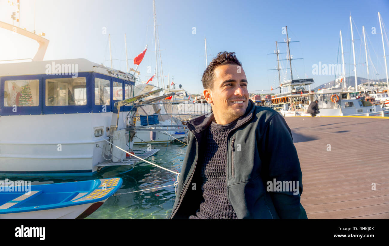 Giovani turche tourist uomo sorridente durante il tramonto a Bodrum marina, Turchia. Barche a vela, marinaio e giornate chiare Foto Stock