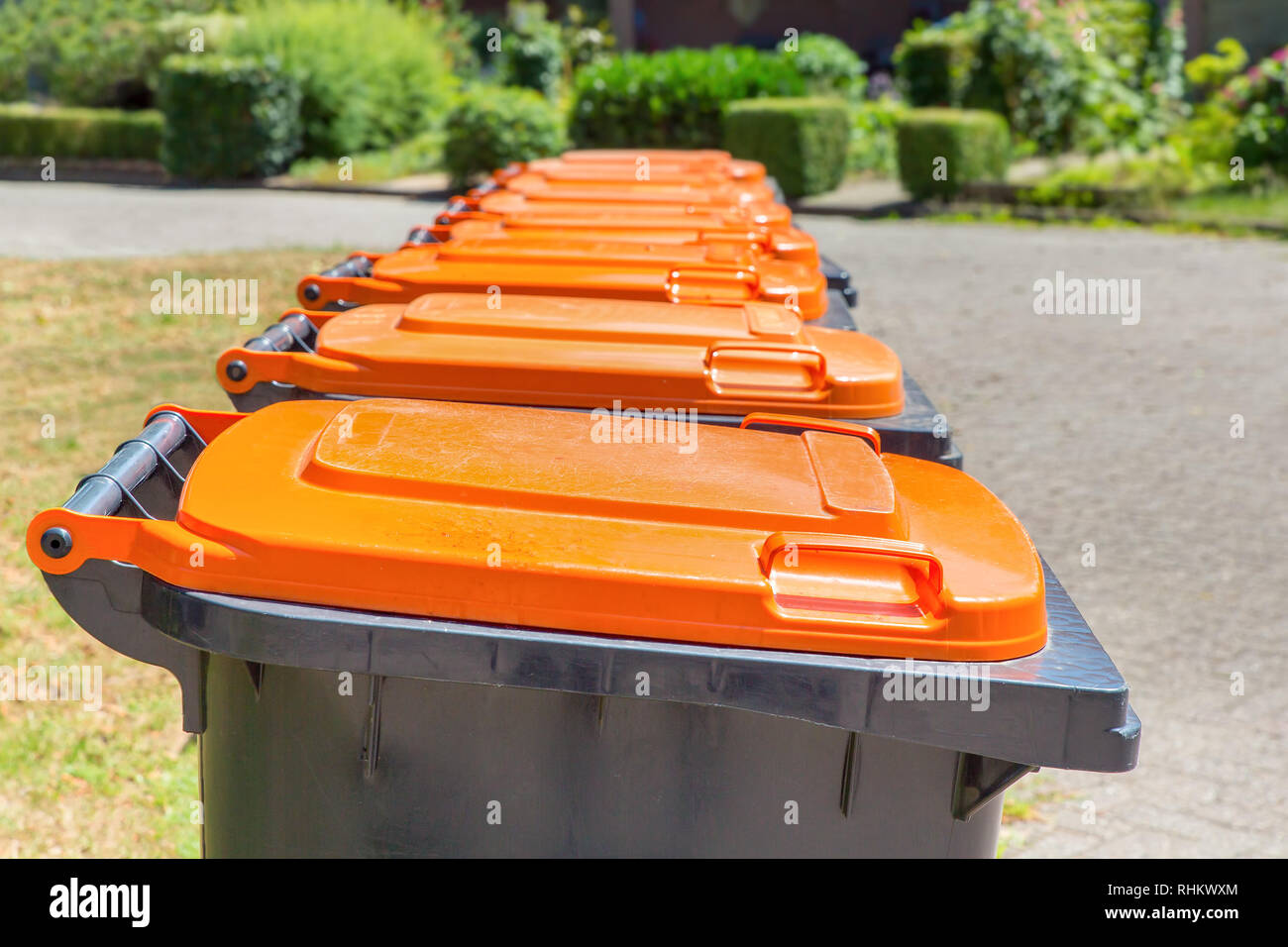 Fila di grigio con orange dei contenitori per i rifiuti di materiale di confezionamento lungo la strada Foto Stock