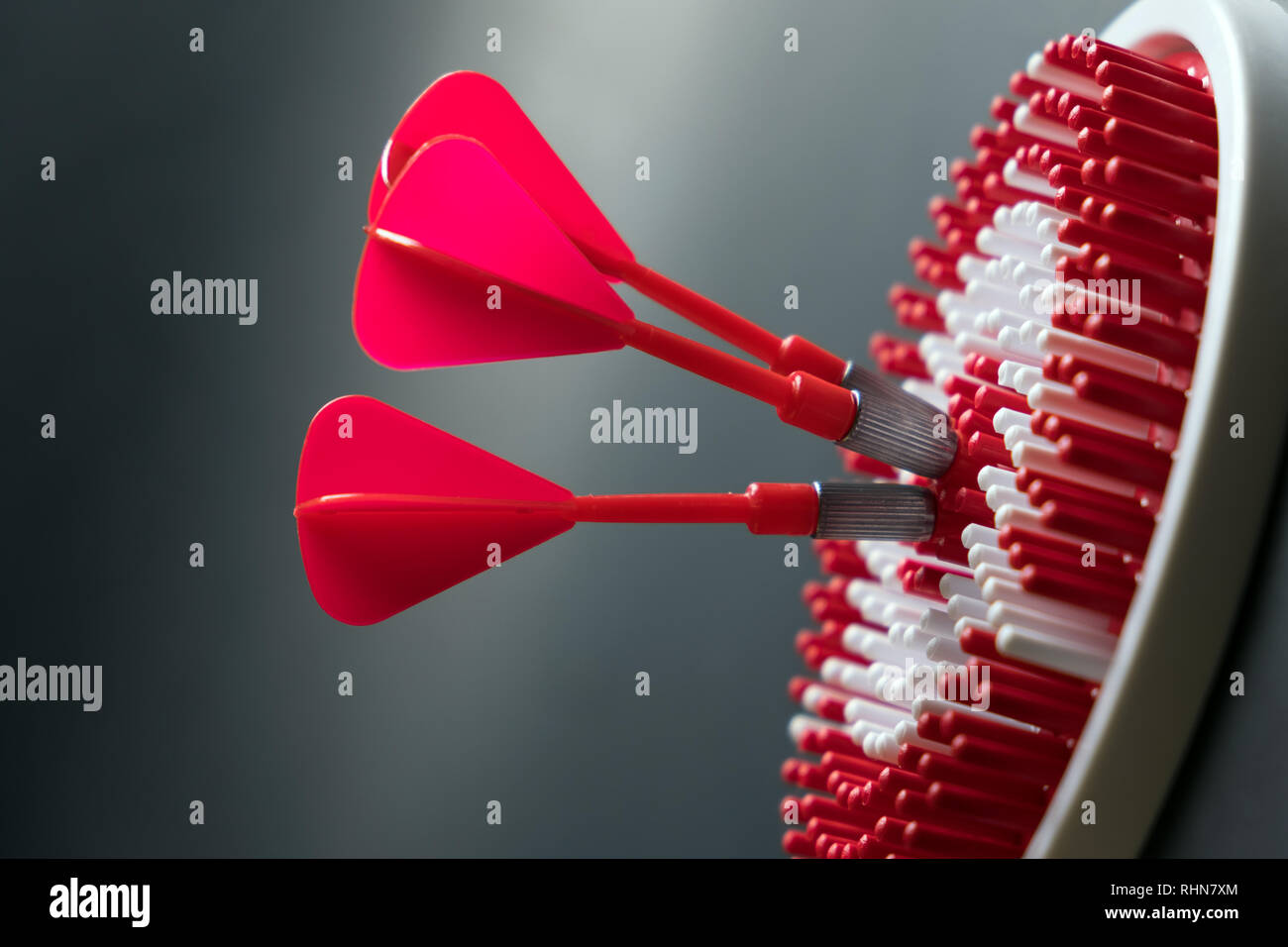 Tre rossi dart frecce di colpire il centro del dartboard per il raggiungimento degli obiettivi concettuali Foto Stock