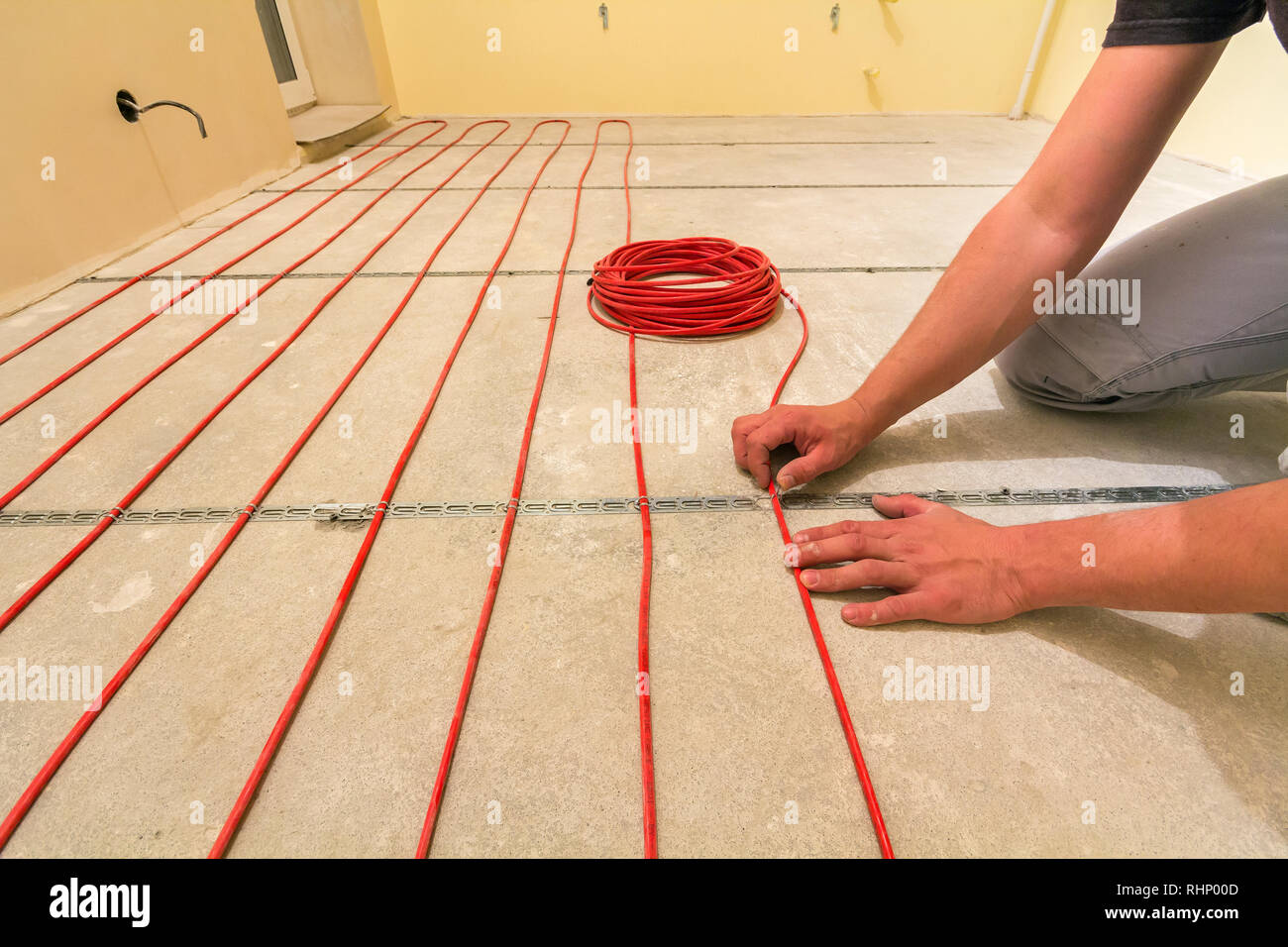 Elettricista installazione di riscaldamento elettrico rosso il filo del cavo  sul pavimento di cemento in camera incompiuto. Ristrutturazione e  costruzione, confortevole casa calda concep Foto stock - Alamy