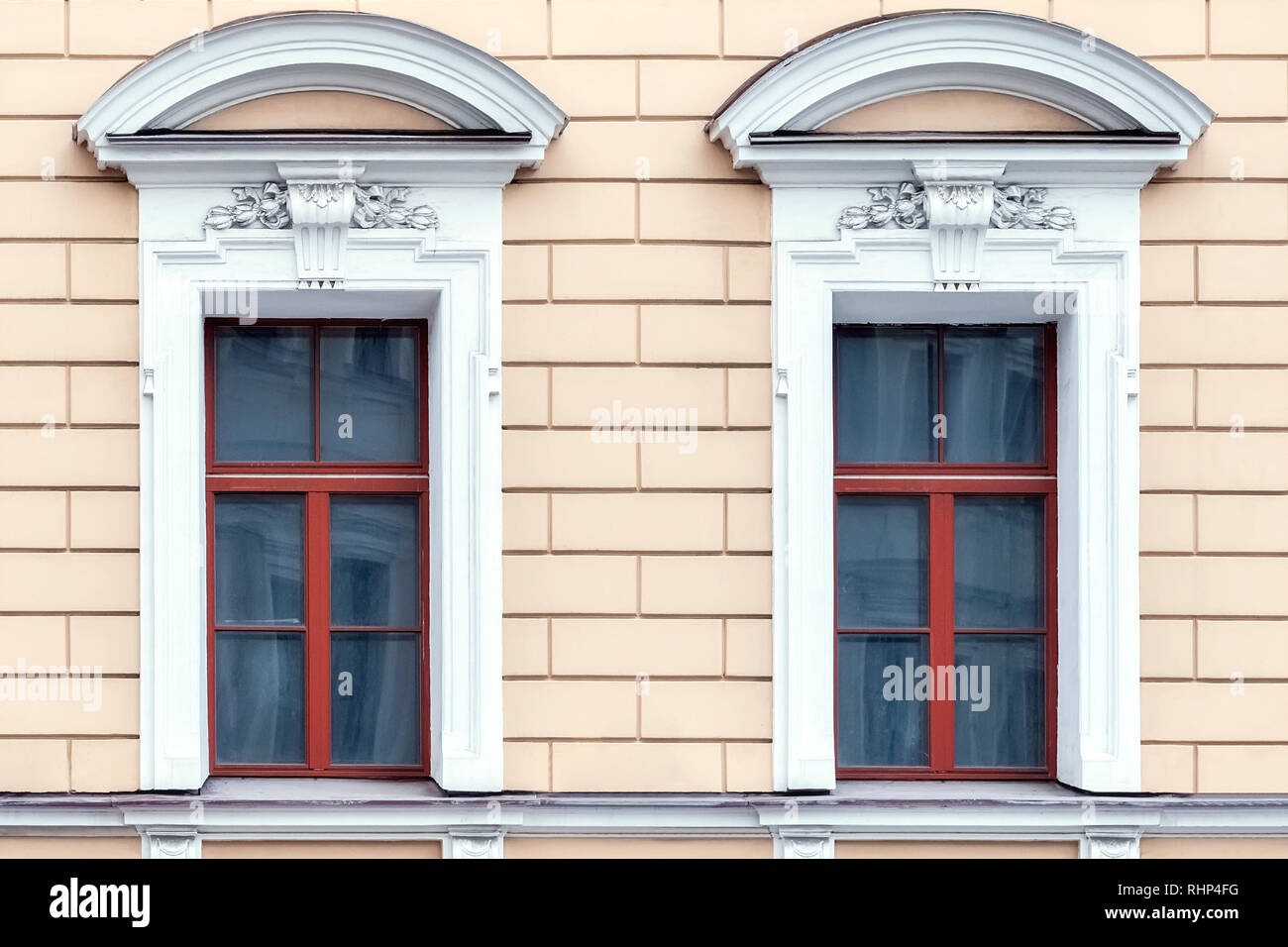 Due finestre rettangolari con un cornicione in forma di un arco di stucco  bianco sullo sfondo di una parete di colore rosa. Da una serie di San  Pietroburgo finestra Foto stock -