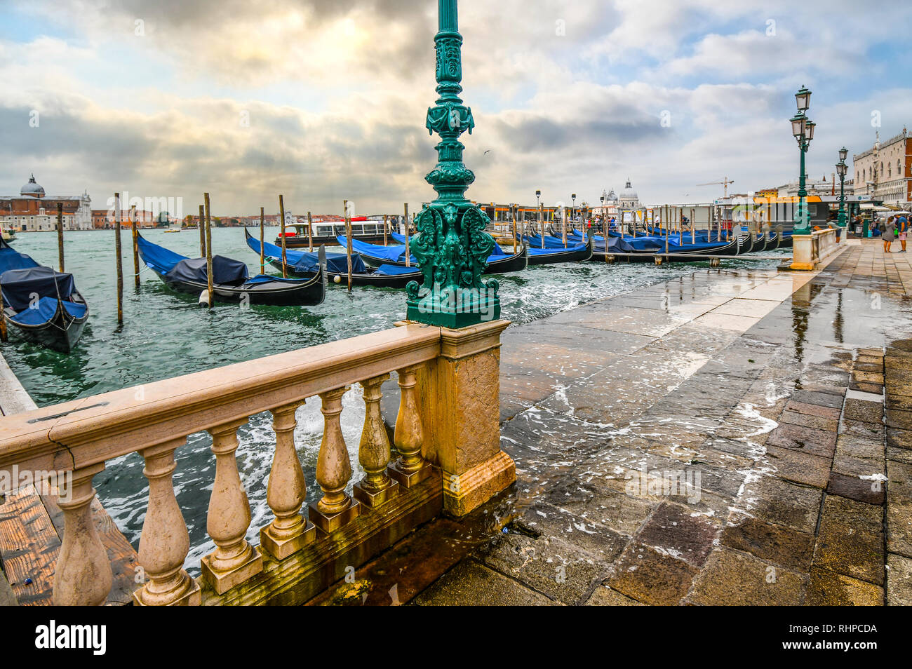 Gondole lungo il Canal Grande la linea in alto lungo la Riva degli Schiavoni passerella veneziana durante l'alta marea, come le acque di esondazione si inclinano a Venezia, Italia Foto Stock