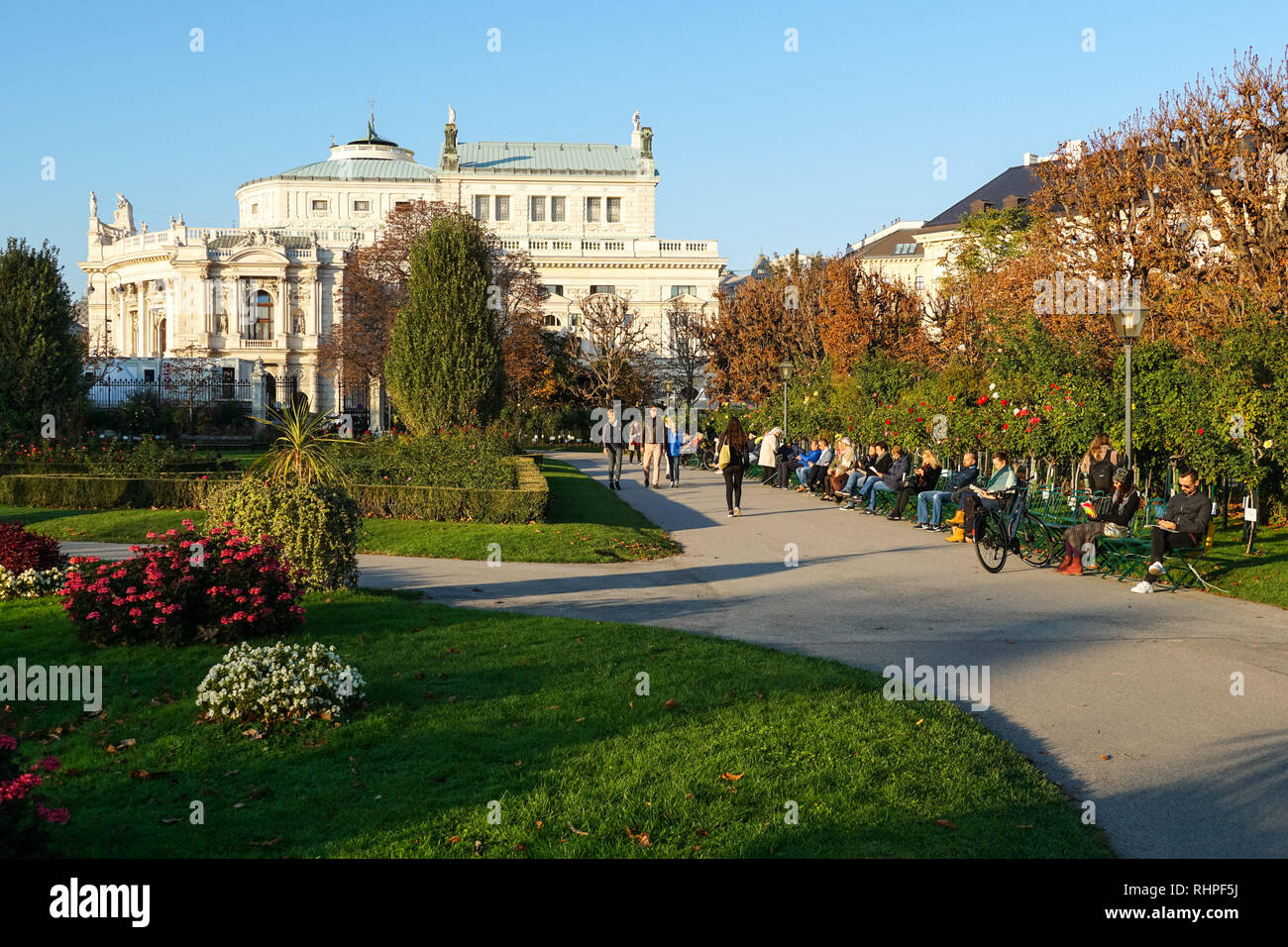 Le persone godono di sunny autunno Meteo Volksgarten Parco e giardino di Vienna in Austria. In background Burgtheater (austriaco Teatro nazionale) Foto Stock