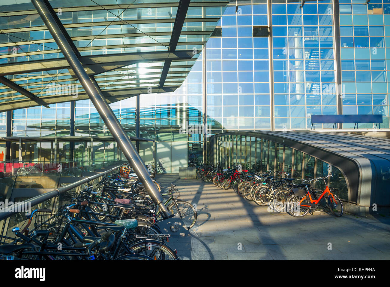 Il parcheggio delle biciclette da Kastrup Airport entrata sotto la tettoia, vetro facciata di edificio in sera sunshine, Copenhagen, Danimarca Foto Stock