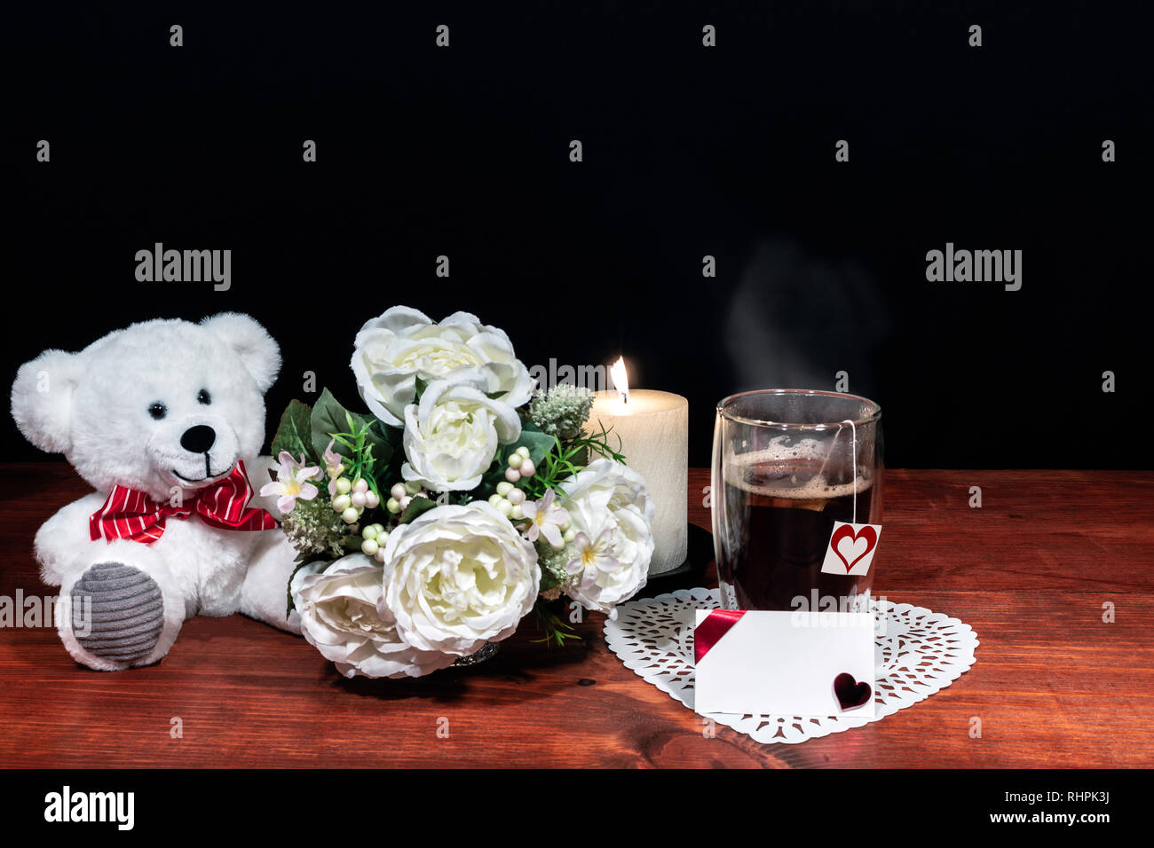 Bouquet di fiori disposti candela bianco su un supporto, un bicchiere caldo di tè su un tavolo di legno. Festa della mamma, Pasqua, valentines, compleanno, Chris Foto Stock