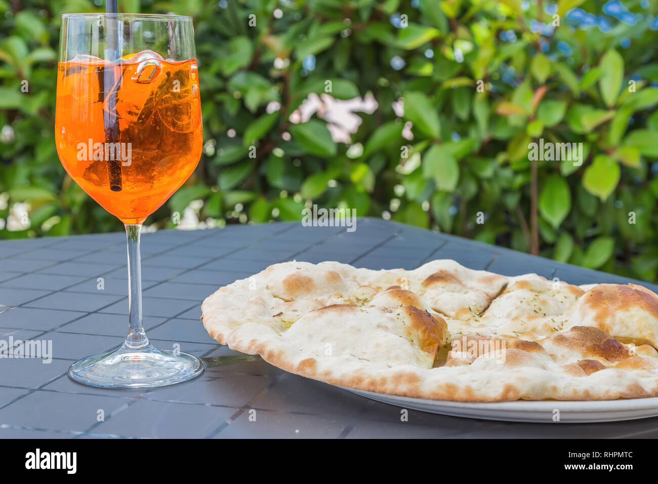 Bicchiere da vino di Aperol Spritz accanto a qualche italiano aglio pane pizza. Foto Stock