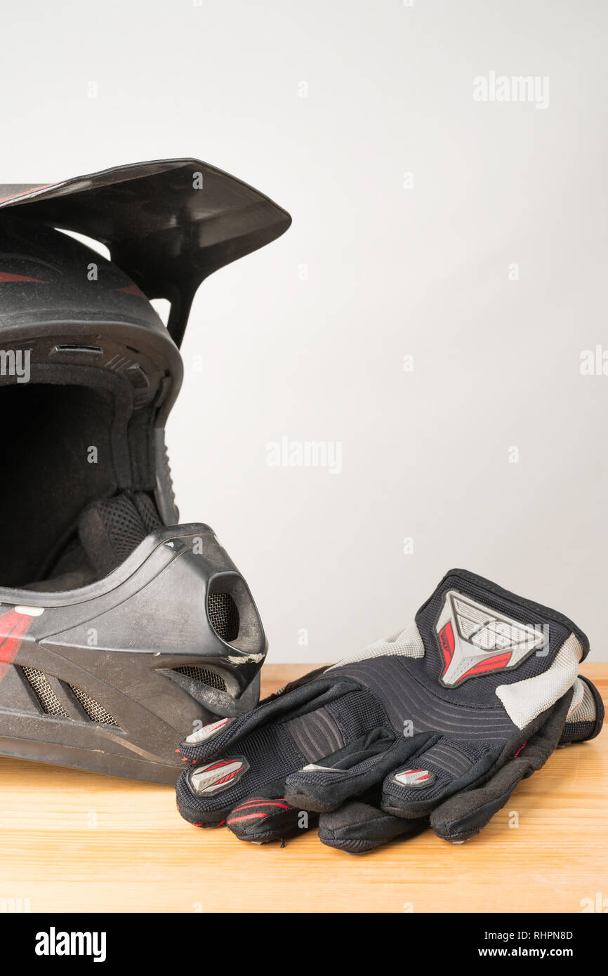 Moto abbigliamento protettivo - motocross casco e guanti di protezione su un sfondo di legno. Orientamento verticale. Copia spazio sulla parte superiore. Foto Stock