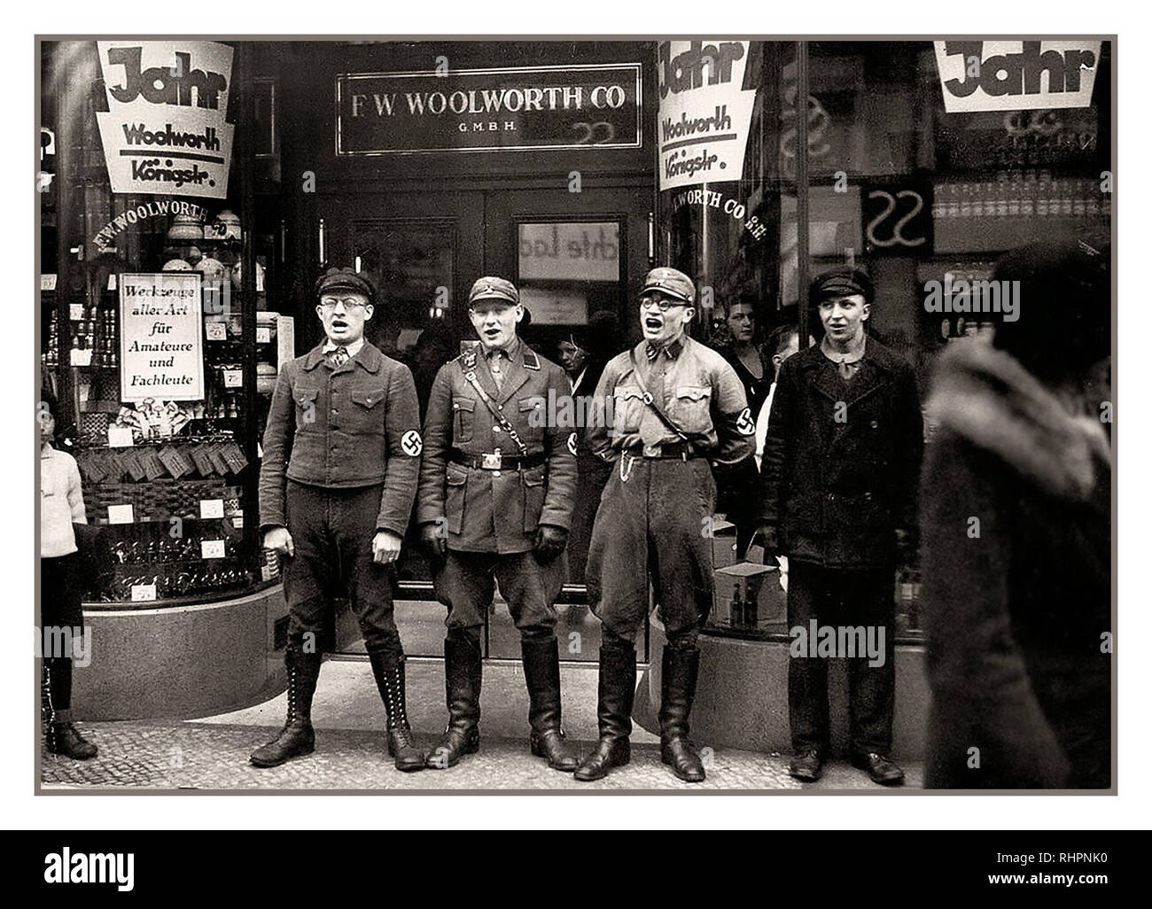 Shop Store degli anni '30 boicottaggio i membri del partito anti-ebrei nazisti e NSDAP Sturmabteilung indulgono nel canto razzista anti-ebraico, all'ingresso del negozio tedesco Woolworth, per promuovere un boicottaggio dei Woolworths Germania 1933, (presumibilmente) di fondazione ebraica. Foto Stock