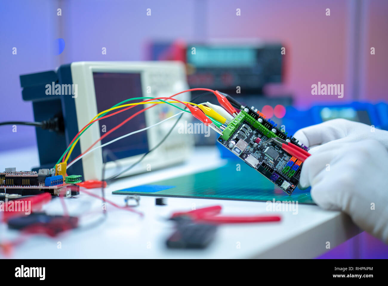 Sviluppo di dispositivi elettronici nel moderno laboratorio di elettronica, su un tavolo, il microprocessore oscilloscopio e multimetro Foto Stock