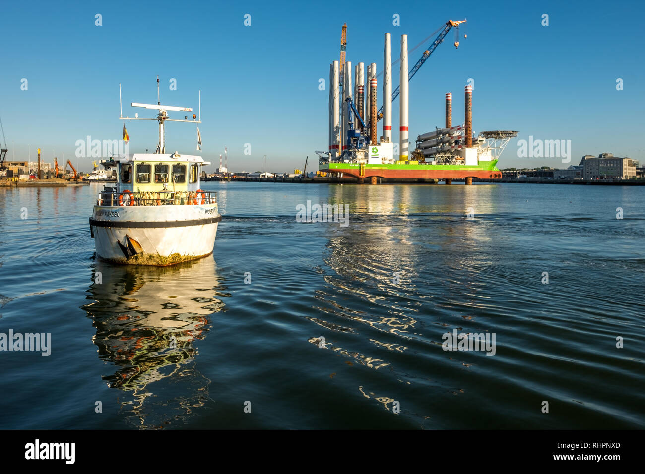 Passeggeri dei traghetti nel porto di Ostenda con sullo sfondo il possente installazione turbina eolica nave 'Sea Installer' Foto Stock