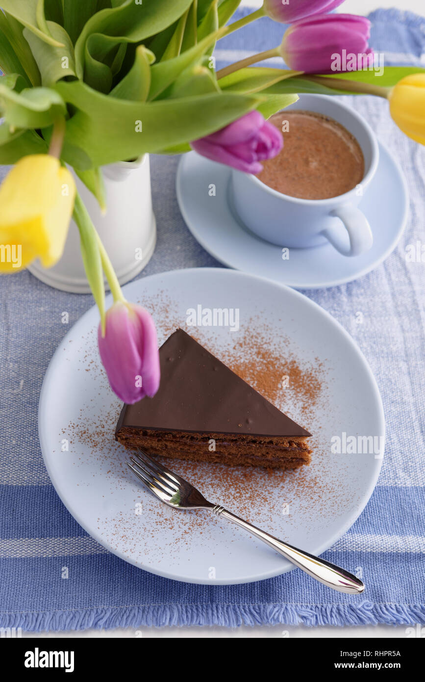 Torta al cioccolato, una tazza di caffè e un mazzo di tulipani Foto Stock