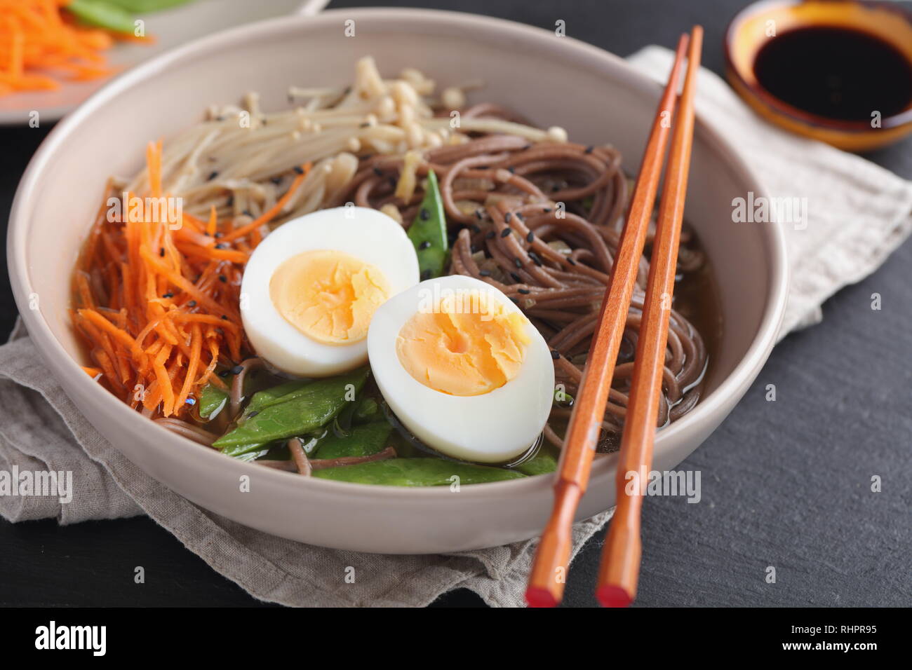 Zuppa giapponese con funghi Enoki, soba noodles, uova sode, carota, Rafano, fagioli verdi e la salsa di soia Foto Stock