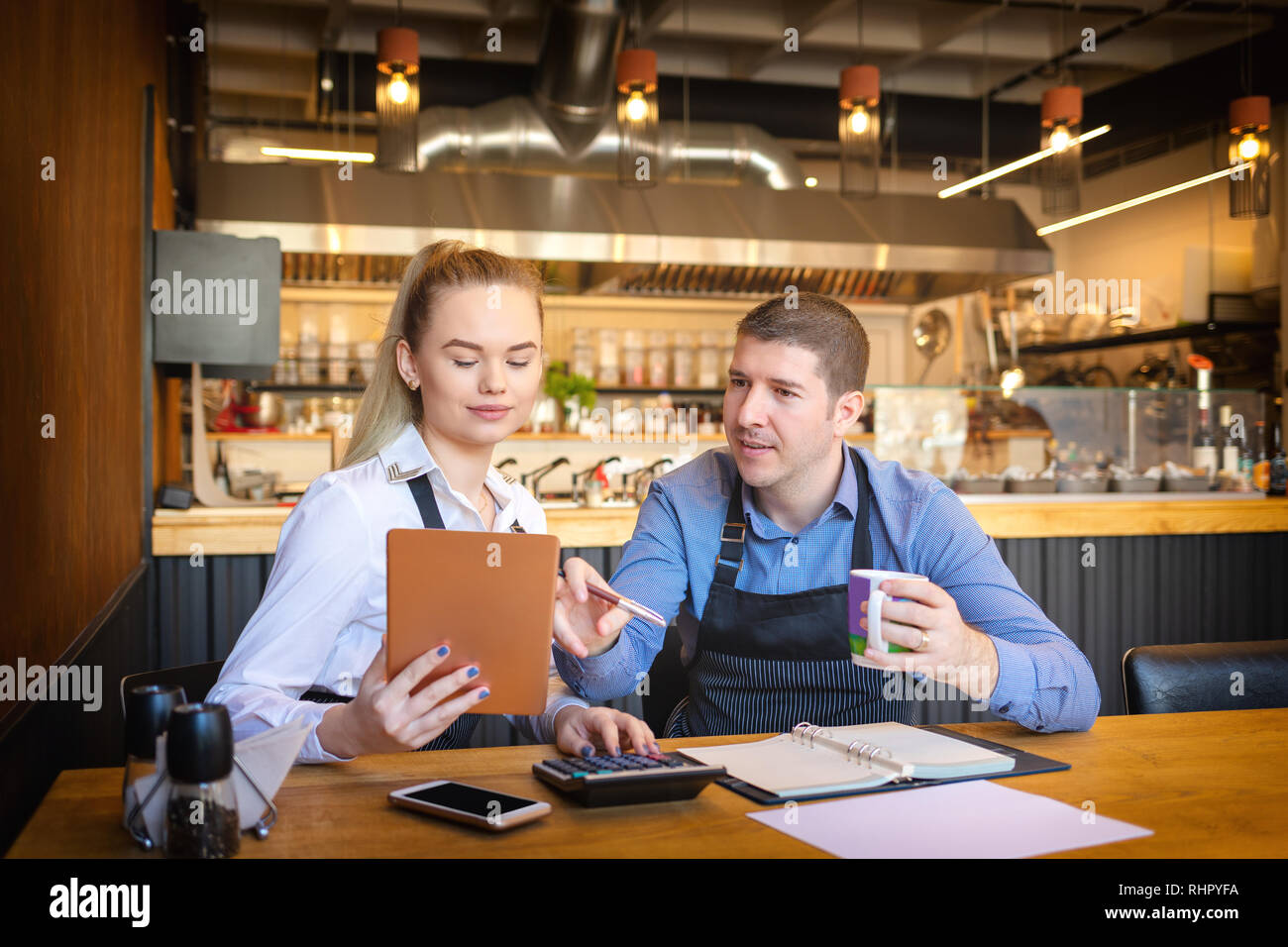 Piccolo ristorante a gestione familiare proprietari il calcolo delle fatture e dei profitti di small business utilizzando tavoletta digitale Foto Stock