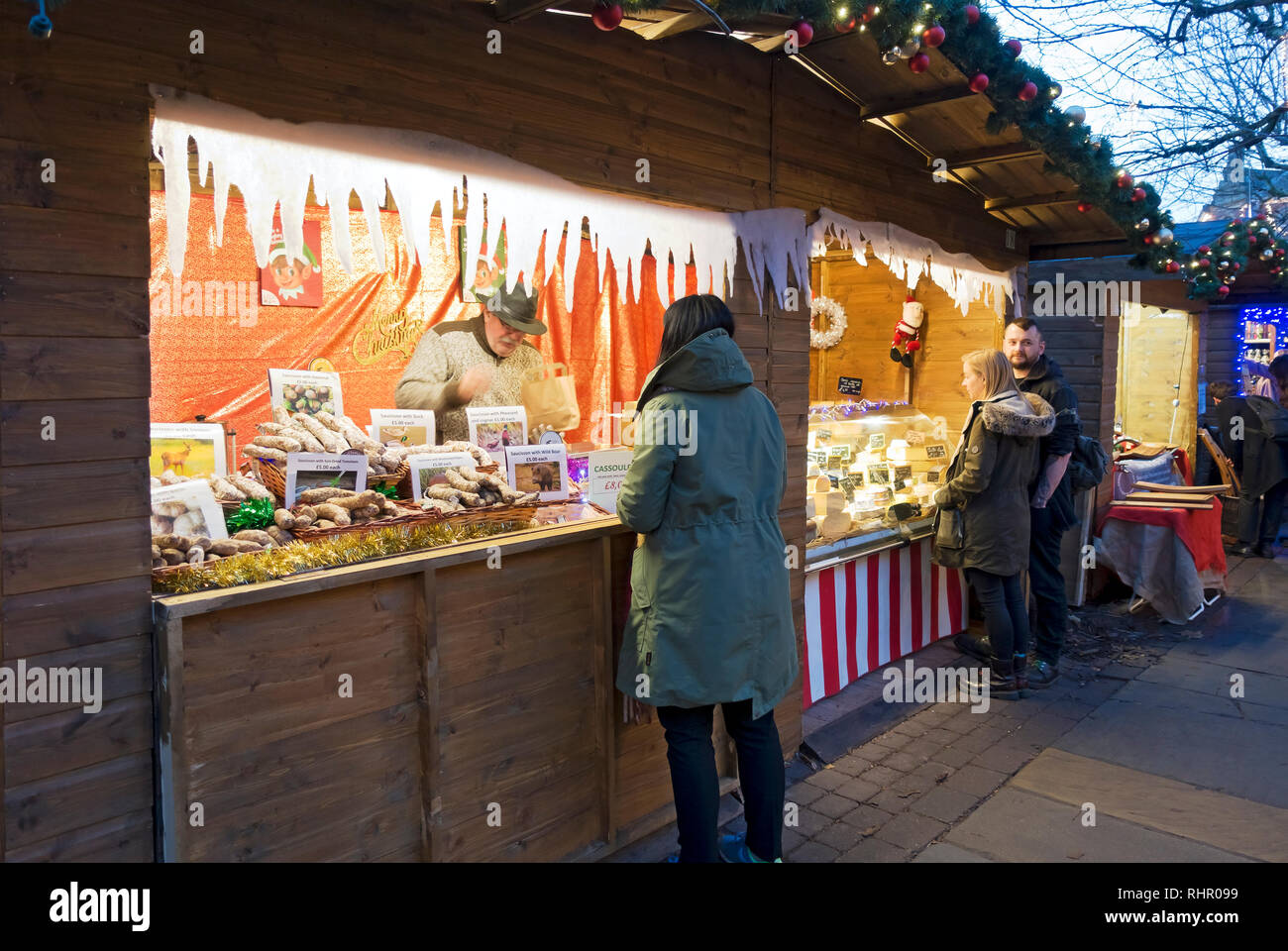 La gente che acquista ai commercianti francesi si ferma al mercato di Natale di St Nicholas Fayre York North Yorkshire Inghilterra Regno Unito GB Gran Bretagna Foto Stock