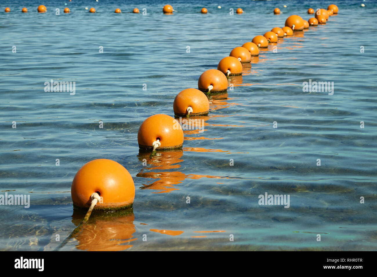 Boe in mare. Vista del mare da un litorale con una lunga linea di colore arancio campo boe galleggianti Foto Stock