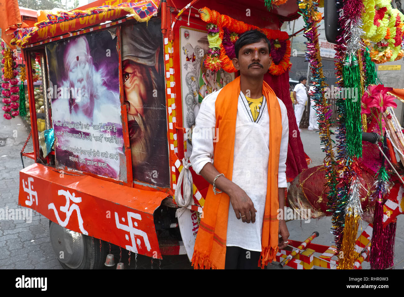 Un uomo che ha trasformato la sua bicicletta in un santuario di santo indiano Sai Baba di Shirdi, il santuario dipinto con una Om (AUM) simbolo e svastiche; Mumbai, India Foto Stock