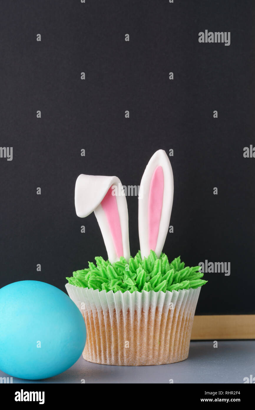 Sfondo di pasqua con orecchie di coniglietto tortina, uovo e lavagna vuota per il testo. Foto Stock
