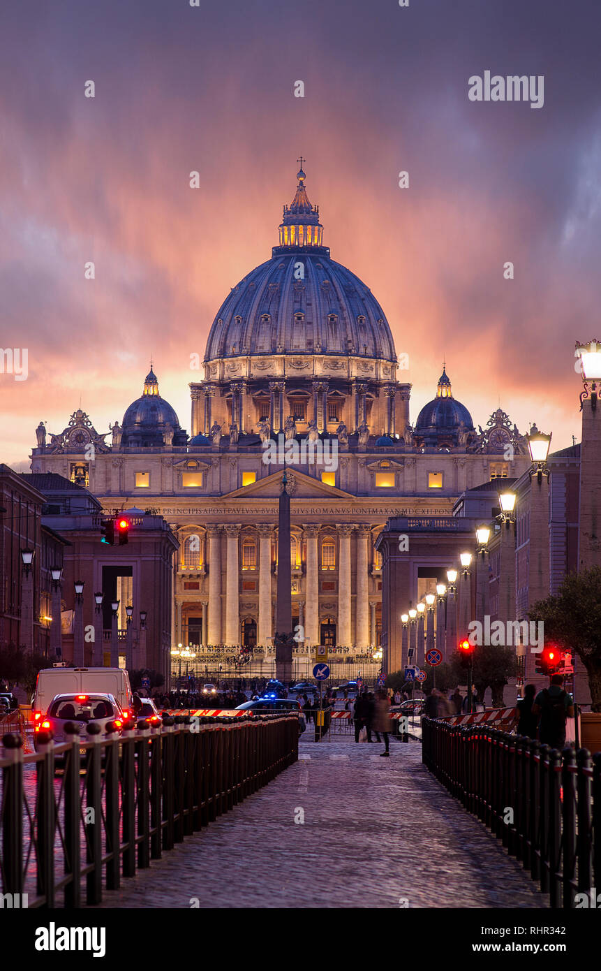 Vista illuminata Basilica di San Pietro e Via della Conciliazione con un bel Cielo di tramonto in arancione nella Città del Vaticano a Roma, Italia. Foto Stock