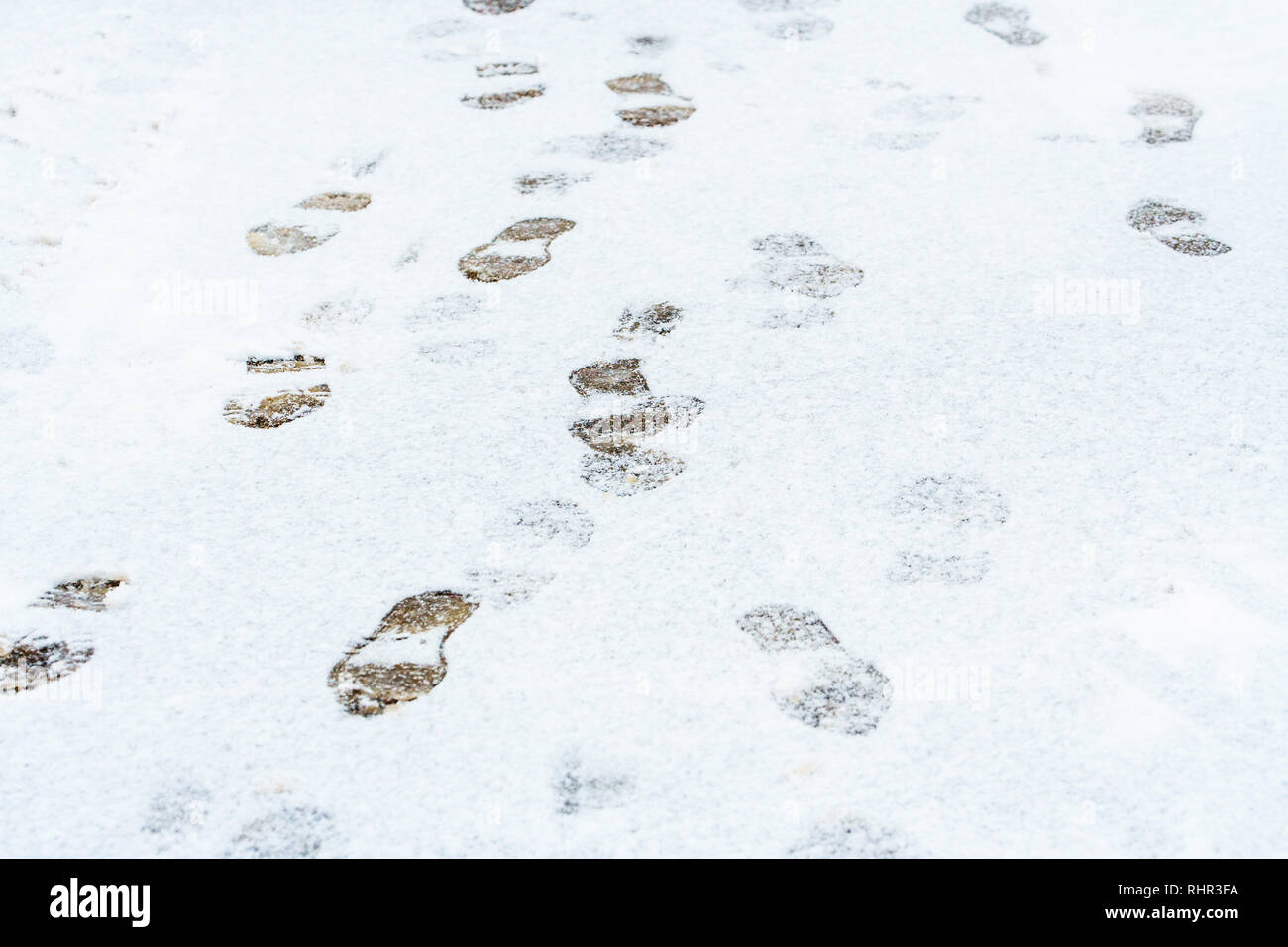 La prima neve sulla strada. Tracce sul marciapiede innevato. Inverno sfondo meteo Foto Stock