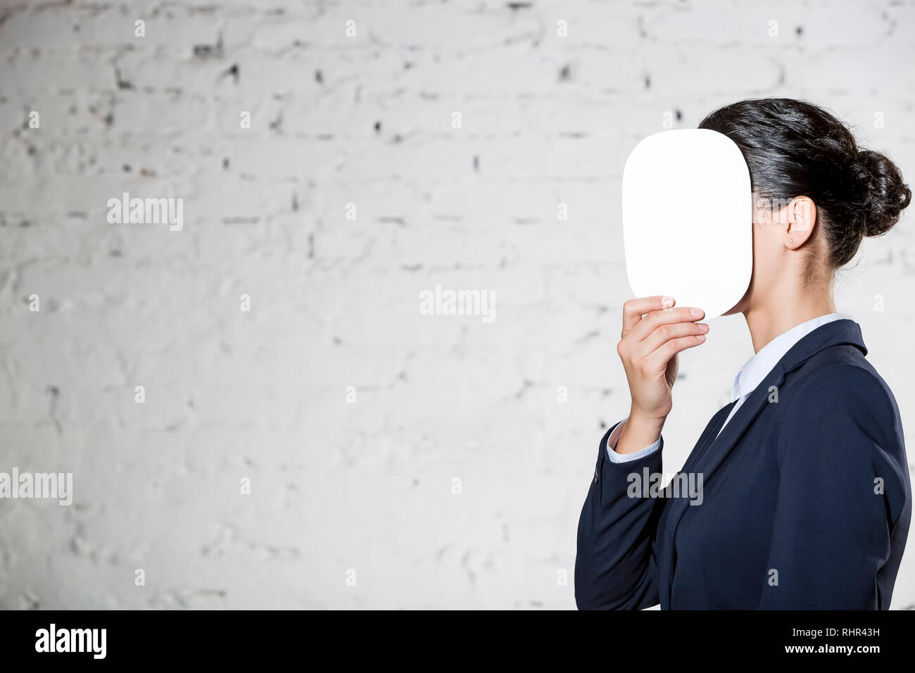 Vista laterale del giovane imprenditrice che ricopre la faccia con carta bianca in ufficio Foto Stock