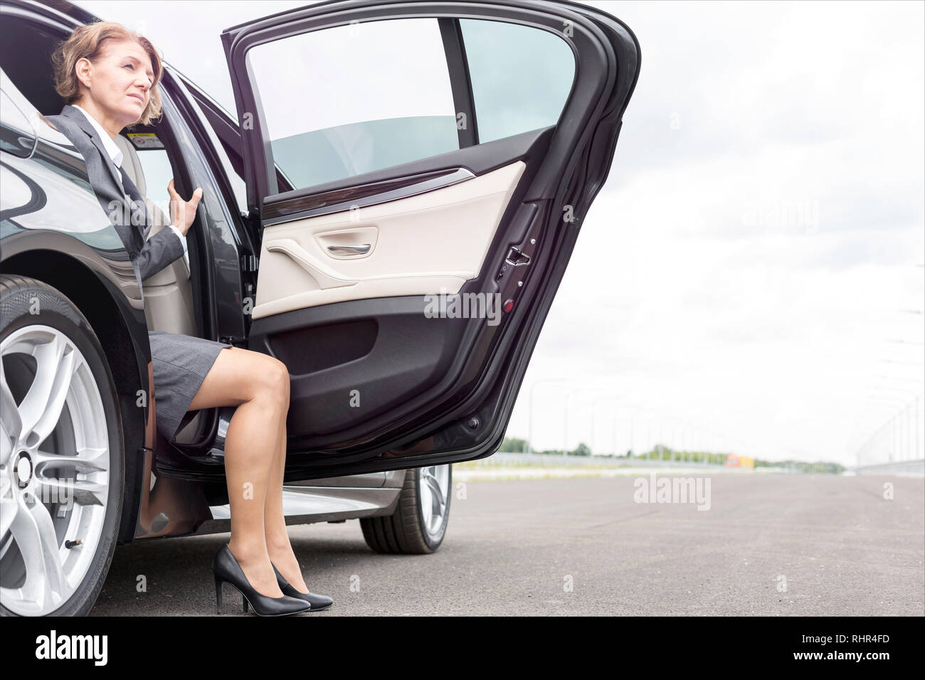Imprenditrice seduti in auto guardando attraverso aprire auto sulla strada Foto Stock