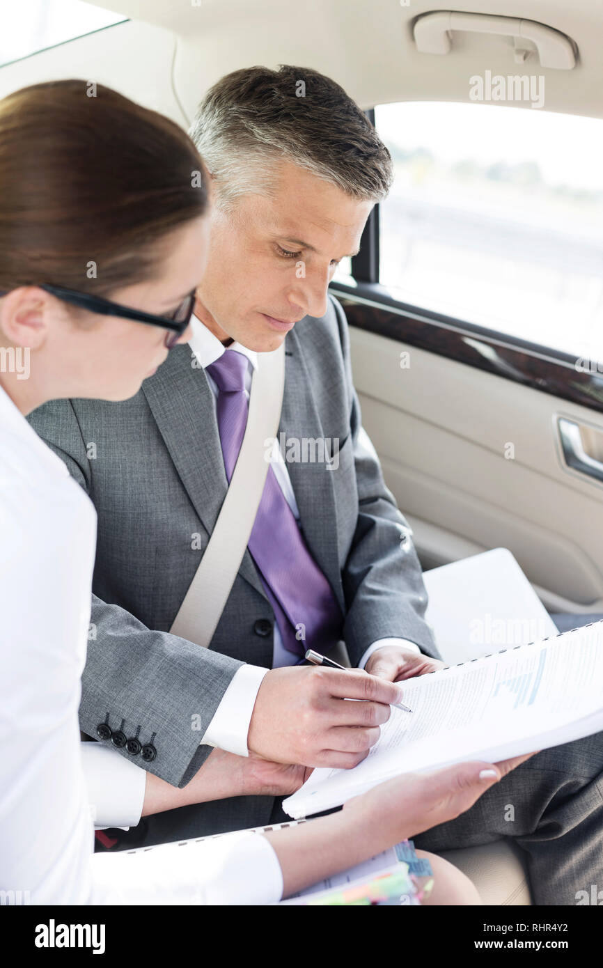 Imprenditore firma di documenti durante la seduta dal collega in auto Foto Stock